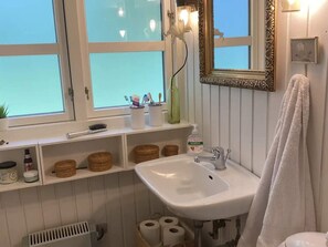 Ein Badezimmer mit einem weißen Waschbecken, einem Spiegel mit aufwendiger Rahmen und einem Fenster mit Blick.