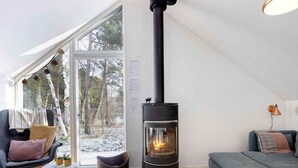 A cozy living room with a fireplace, a sofa, a chair, and a dining table. - 5 Star Holiday Home in Hals (Hals)