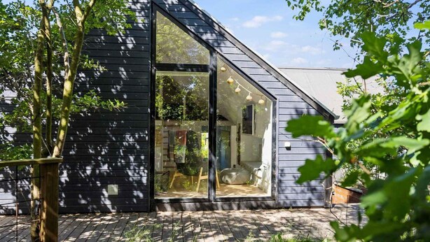 A modern house with a large glass door, a wooden deck, and a garden. - 5 Star Holiday Home in Hals (Hals)