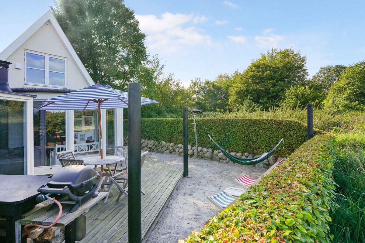 A deck with outdoor furniture, a hammock, and a covered seating area with a striped umbrella.