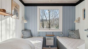 A bedroom with two beds, a window with a view of trees, and a ceiling fan. - 5 Star Holiday Home in Ronne (Ronne)