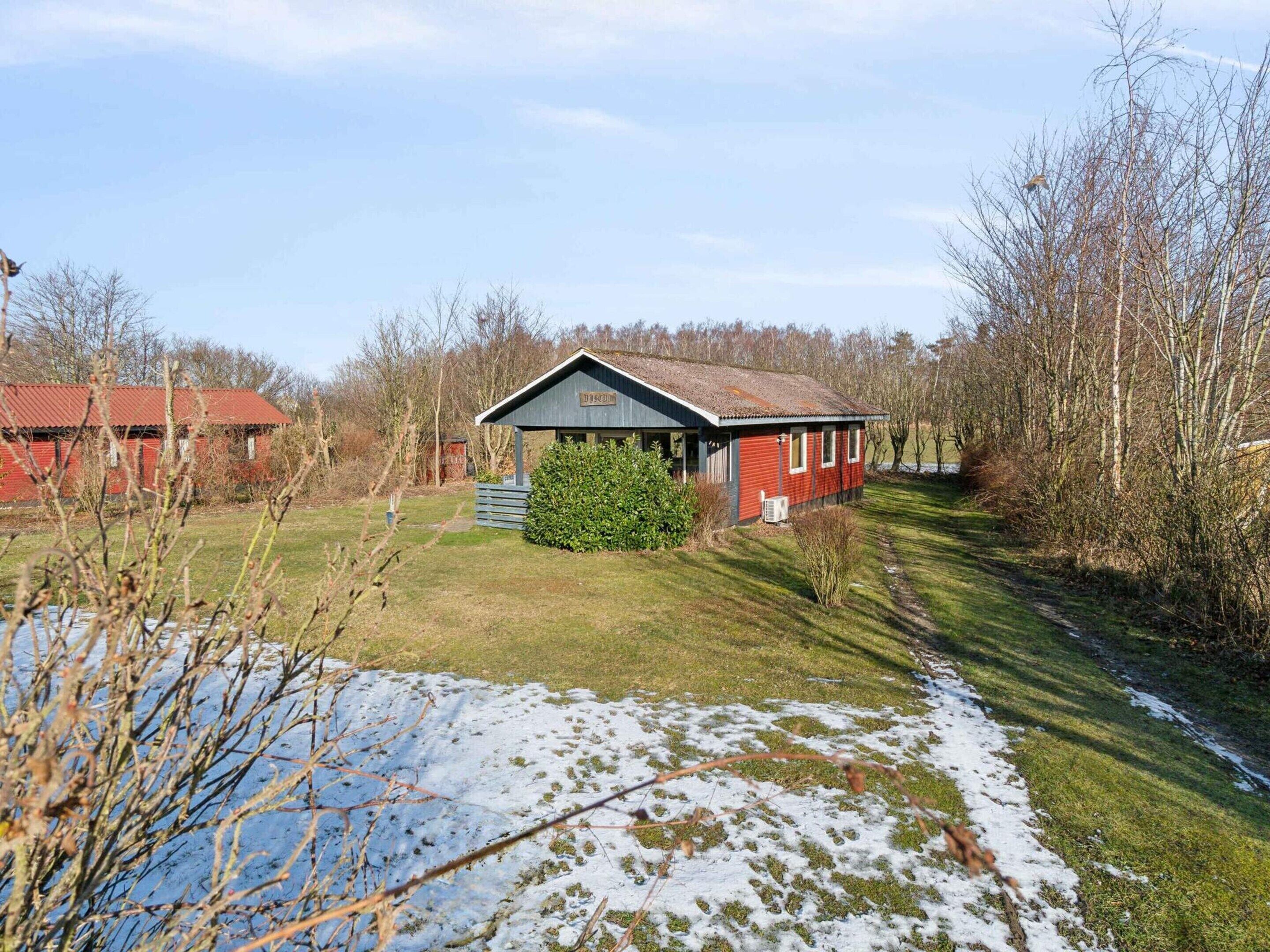 A red building with a sloped roof, surrounded by trees and a grassy area.