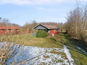 Ein rotes Gebäude mit einem geneigten Dach, umgeben von Bäumen und einer Rasenfläche.