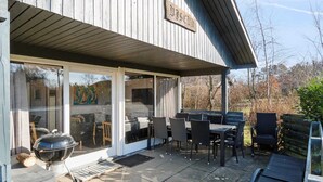 A covered patio with outdoor furniture, a grill, and a wooden deck. - 5 Star Holiday Home in Ronne (Ronne)