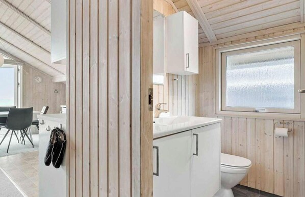 A modern bathroom with wooden paneling, a white sink, and a toilet. - 5 Star Holiday Home in Otterup (Otterup)