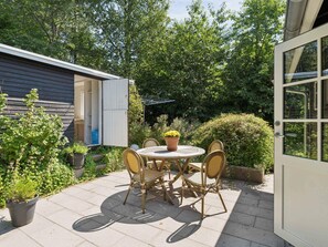 A patio with a round table and four chairs, surrounded by potted plants and a wooden fence. - 4 Star Holiday Home in Vejby (Vejby)