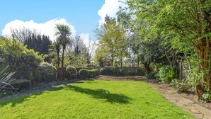 A well-maintained grassy lawn with a stone pathway leading to a wooden fence. - Elegant Ealing Apartment Retreat (Cape Town)