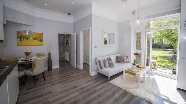 A modern kitchen with a dining area, a sofa, and a view of the garden. - Elegant Ealing Apartment Retreat (Cape Town)