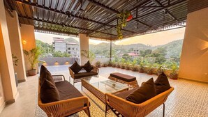 Une terrasse sur le toit, aménagée avec des meubles en osier, des plantes en pot et offrant une vue sur le paysage environnant.