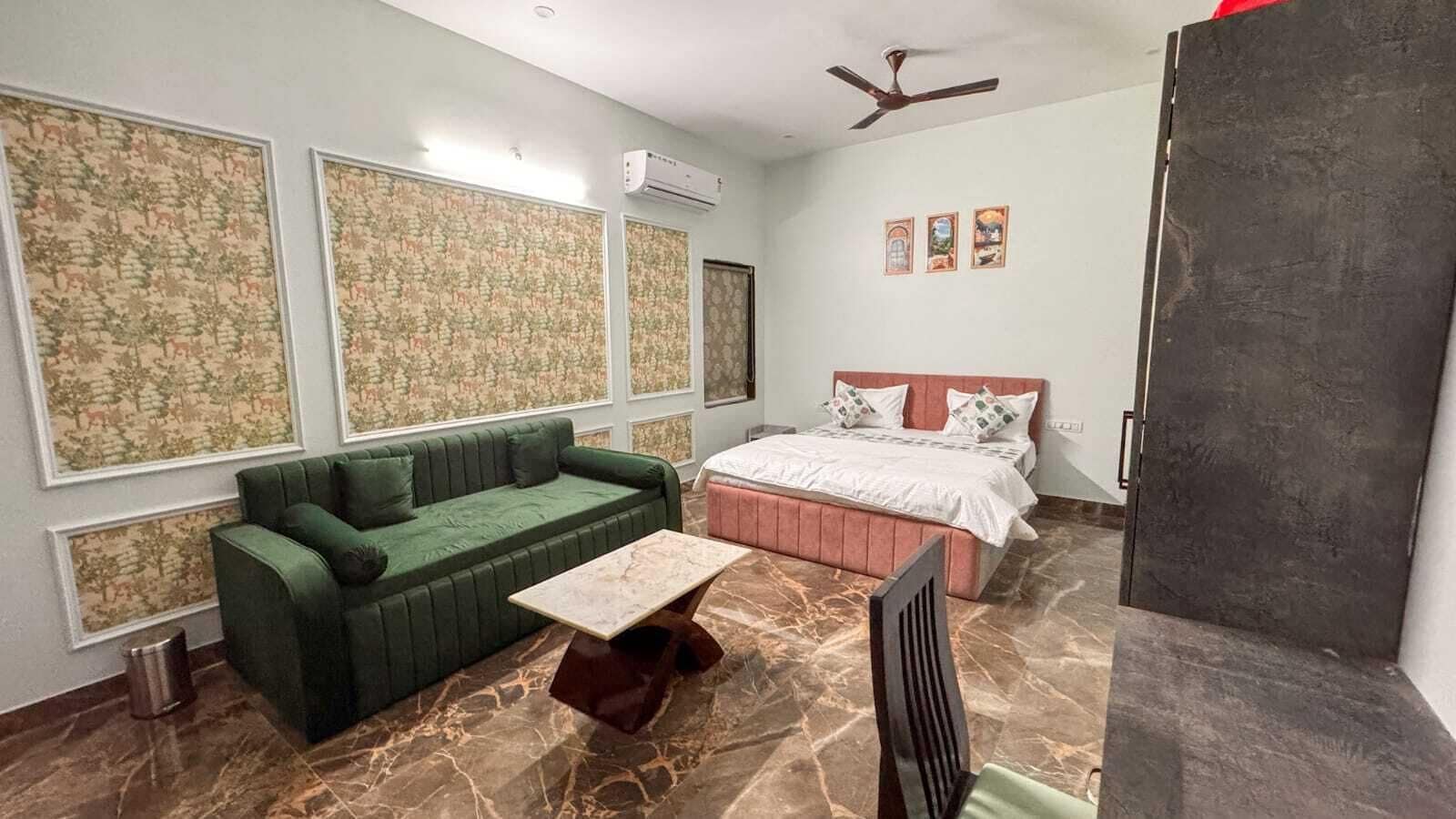 A room with a green sofa, a bed with white bedding, a marble floor, and a ceiling fan.