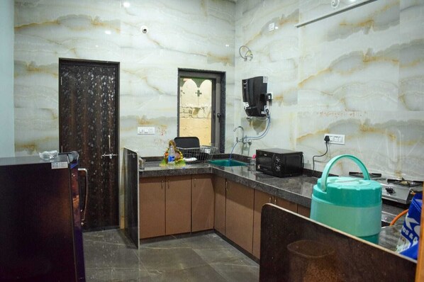 A kitchen with a marble backsplash, a built-in oven, a sink, and a stove. - Green Vista Farms (Udaipur)