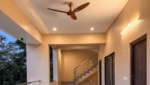 Un intérieur moderne avec un escalier, un ventilateur de plafond et des plantes en pot.