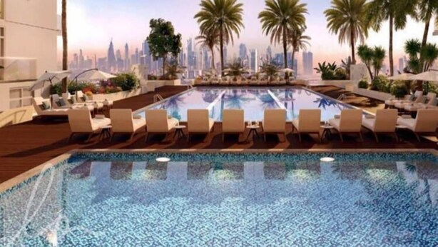 Piscina com espreguiçadeiras e palmeiras, emoldurada por um horizonte urbano.