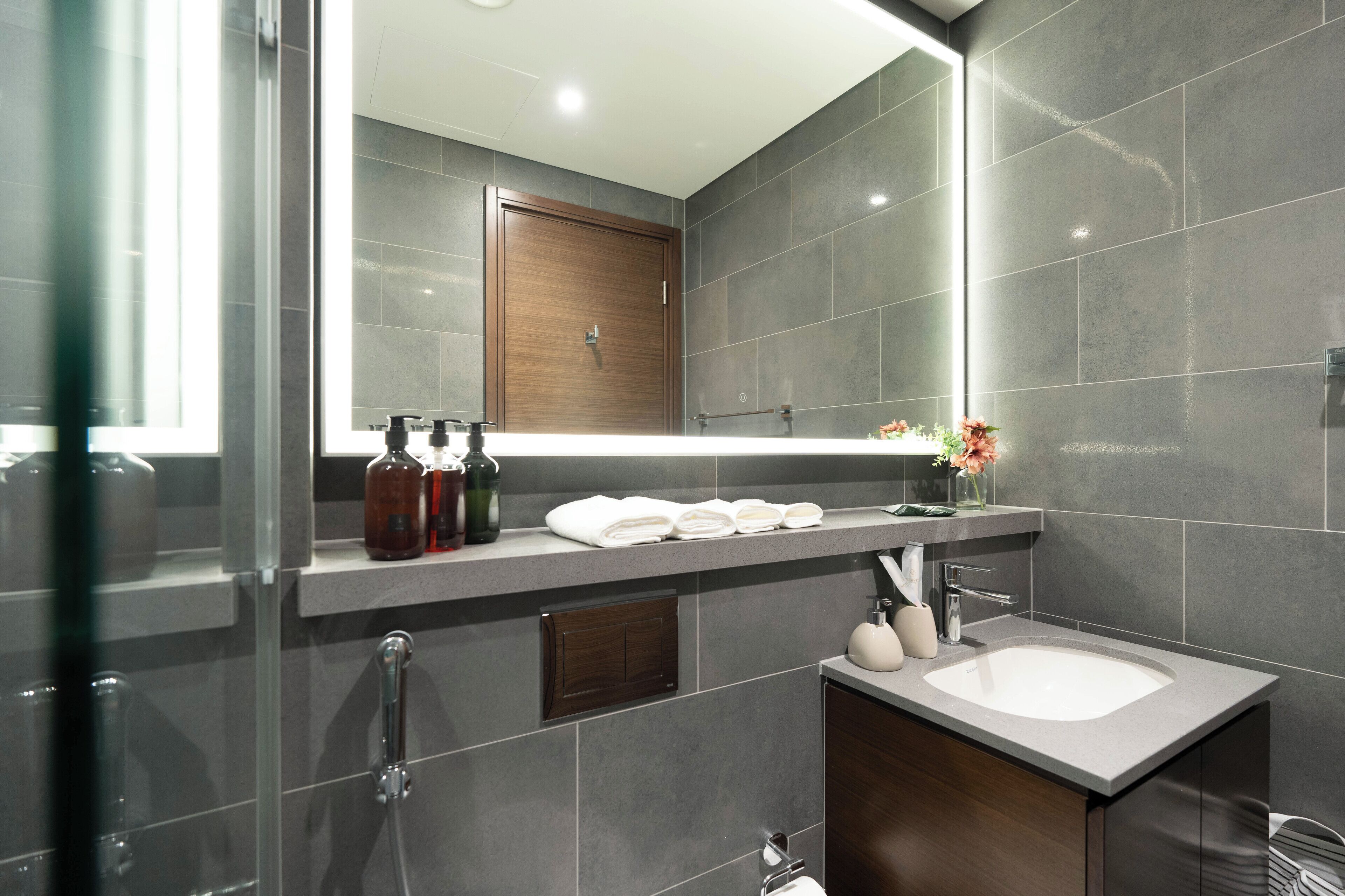 A modern bathroom with a large mirror, a sink, and a shower.