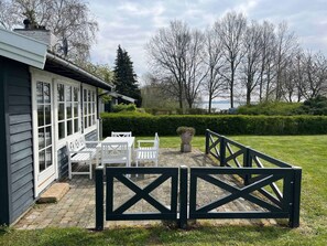 A house with a patio area featuring white outdoor furniture and a black gate. - 5 Star Holiday Home in Kirke Hyllinge (Kirke Hyllinge)