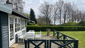 A house with a patio area featuring white outdoor furniture and a black gate. - 5 Star Holiday Home in Kirke Hyllinge (Kirke Hyllinge)
