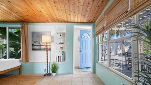 A room with a bed, a lamp, a bookshelf, and a door leading to an outdoor area with a view. - Private Beach Access Sauna Outdoor Fireplace (St. Augustine)