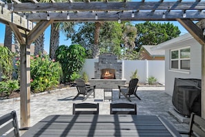 Un patio al aire libre con chimenea de piedra, pérgola de madera y zona de estar.