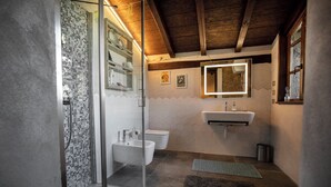 Ein Badezimmer mit Duschkabine aus Glas, zwei Waschbecken, einem Spiegel und einem Fliesenboden.