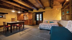Ein gemütliches Zimmer mit einem Bett, einem Esstisch mit Stühlen und einer Küchenzeile.