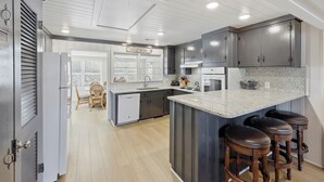 Cozinha moderna com ilha central, banquetas e área de jantar com uma cadeira e mesa.