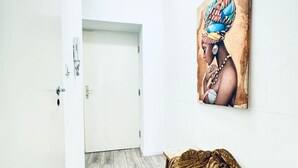 A room with a white door, a wooden floor, a bed with a brown blanket, and a wall-mounted painting. - Comfortable and Affordable Palace Studio (Vienna)