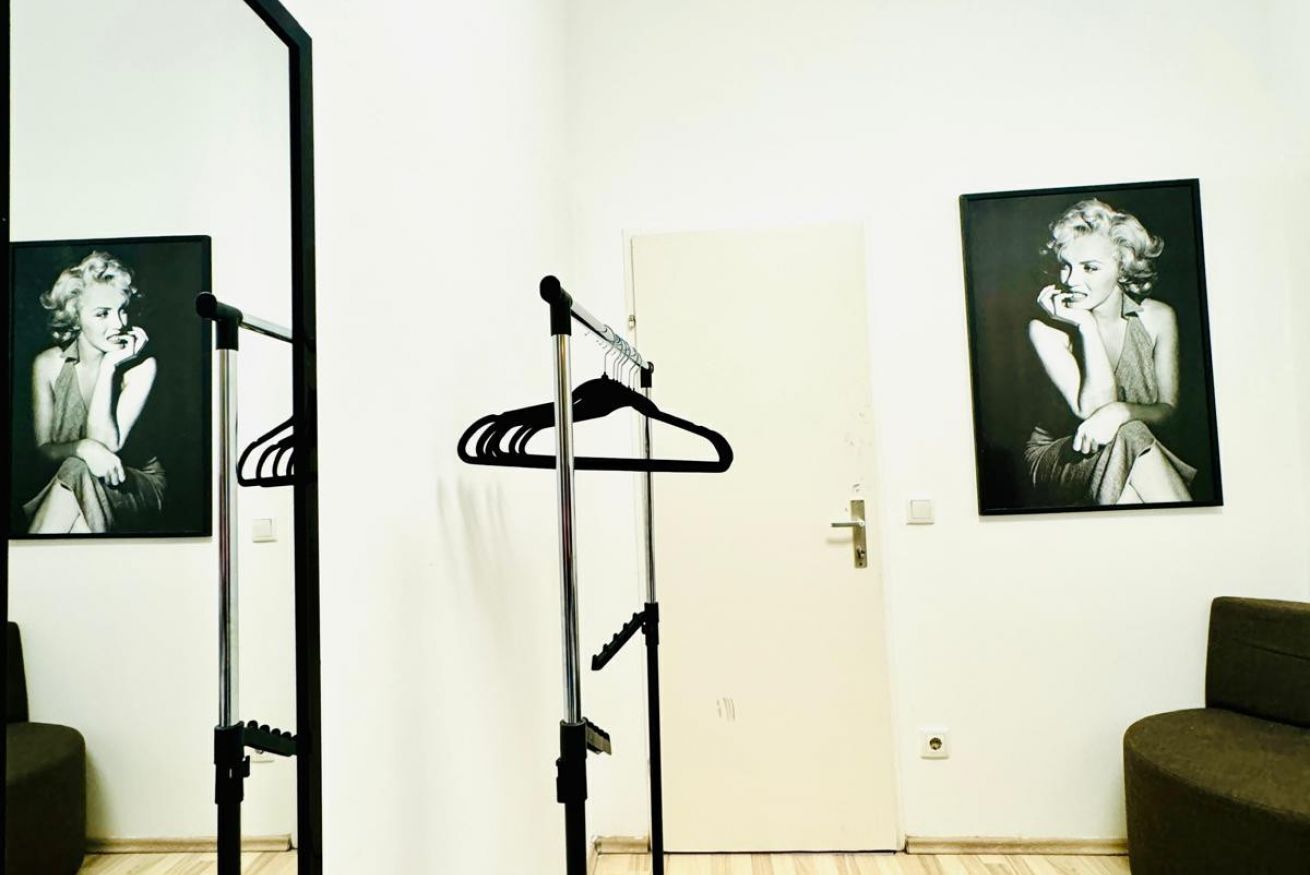 A room with a door, a coat rack, and two framed pictures on the wall.