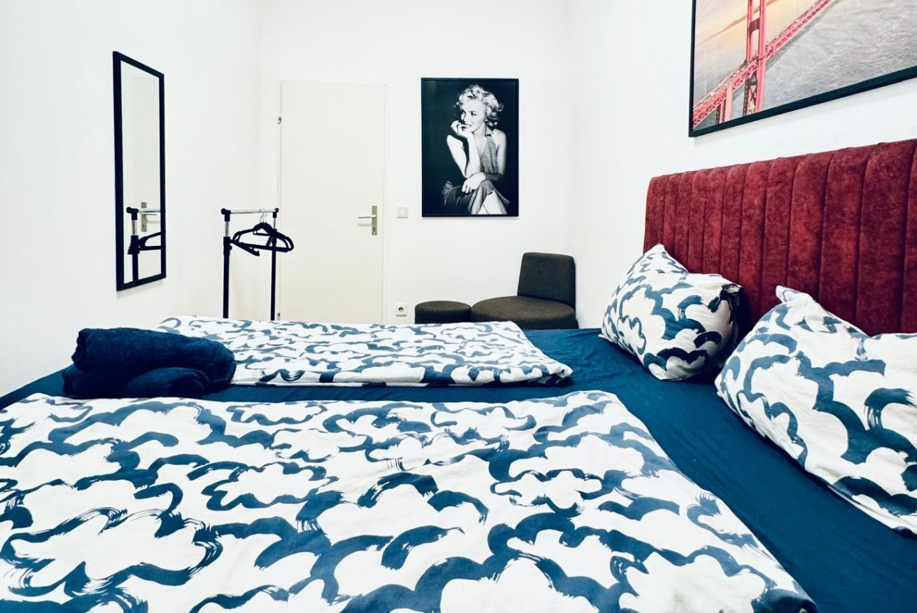 A bedroom with a bed, a red headboard, a black and white framed picture, and a door.