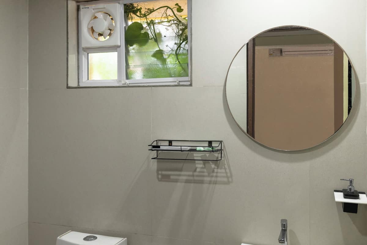 Ein Badezimmer mit Toilette, Waschbecken und Fenster mit Blick ins Grüne.