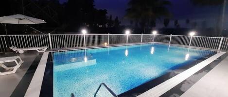 A rectangular swimming pool with a white border and a metal ladder.