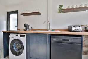 A compact kitchen with a washing machine, dishwasher, and a toaster. - Cosy 3-bedroom House Near Caerphilly Castle (Caerphilly)