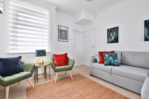 A modern living room with a grey sofa, green armchairs, and a small table with a lamp. - Cosy 3-bedroom House Near Caerphilly Castle (Caerphilly)