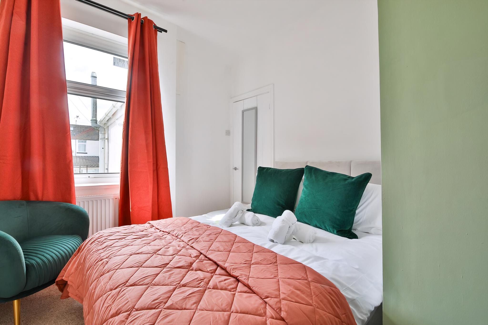 A hotel room with a bed, a chair, and a window with curtains.