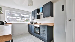Una cocina moderna con ventana, horno empotrado, microondas y armarios oscuros.