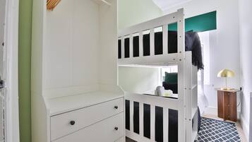 A bunk bed with a white frame, a small wooden side table, and a patterned rug.