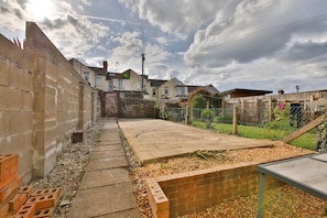 A residential area with a paved pathway, a brick wall, and a fenced garden. - Cosy 3-bedroom House Near Caerphilly Castle (Caerphilly)