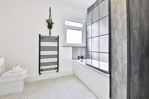 A bathroom with a white toilet, a black towel rack, a window, and a tiled floor. - Cosy 3-bedroom House Near Caerphilly Castle (Caerphilly)