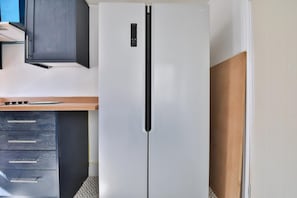 A kitchen with a white refrigerator, wooden countertop, and dark cabinets. - Cosy 3-bedroom House Near Caerphilly Castle (Caerphilly)