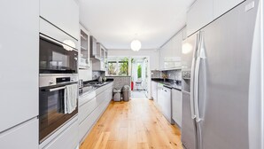 Une cuisine moderne dotée d’appareils électroménagers en acier inoxydable, de meubles blancs et d’un plancher en bois.