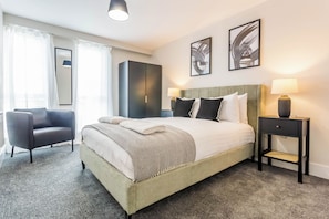 A hotel room with a bed, a chair, a wardrobe, and two bedside lamps. - Toast Stays - The Elm at Parsons House (Washington)