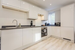 A modern kitchen with white cabinets, a stainless steel sink, and a built-in oven. - Toast Stays - The Elm at Parsons House (Washington)