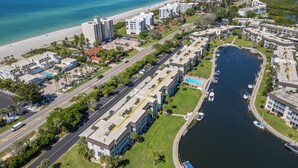 An aerial view of a coastal hotel area with a marina, a beach, and a road.