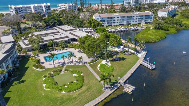 An aerial view of a resort with a swimming pool, a dock, and a marina.