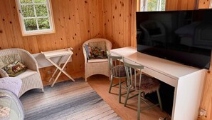 A cozy room with wooden walls, a large flat-screen TV, wicker furniture, and a striped rug. - 4 Star Holiday Home in Skaelskor (Skælskør)