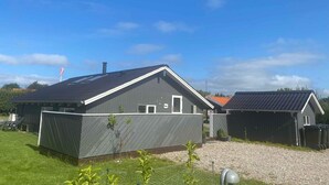 A modern two-story house with a sloped roof, a fenced yard, and a gravel driveway. - 4 Star Holiday Home in Skaelskor (Skælskør)