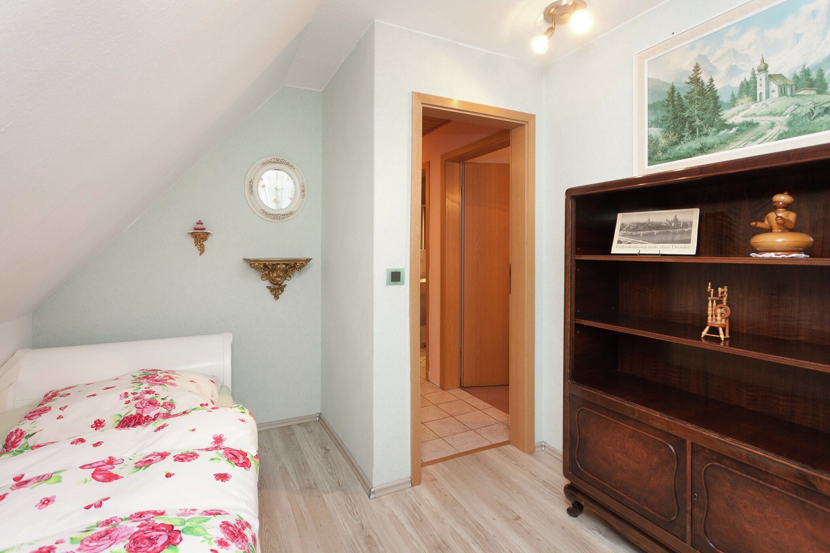 Une chambre à coucher avec un lit, une bibliothèque en bois, un tableau et un miroir au mur.