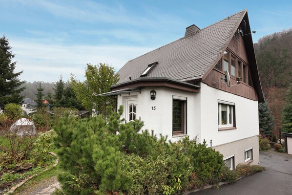 A two-story house with a sloped roof, a visible number '15' on the side, and a satellite dish on the roof.