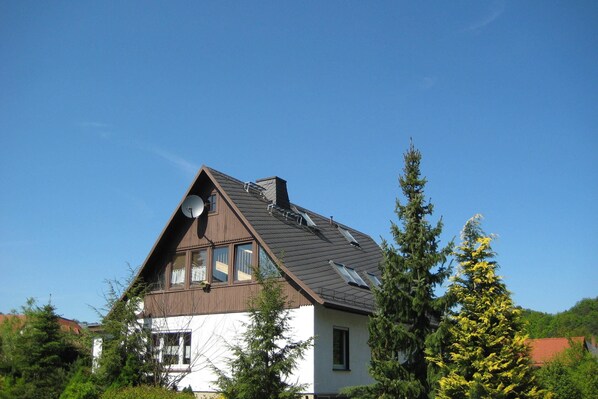 A house with a sloped roof, satellite dish, and large windows.
