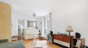 Un salon spacieux avec un piano, un grand miroir, une lampe et une bibliothèque.