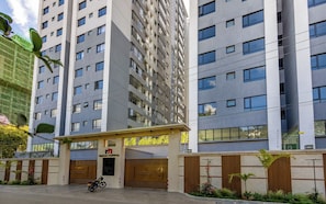 A modern high-rise building with a gated entrance, a sign for Neptune Residency, and a motorcycle parked in front. - Chic One Bedroom with Swimming Pool, Gym and magnificent City Views (Nairobi)